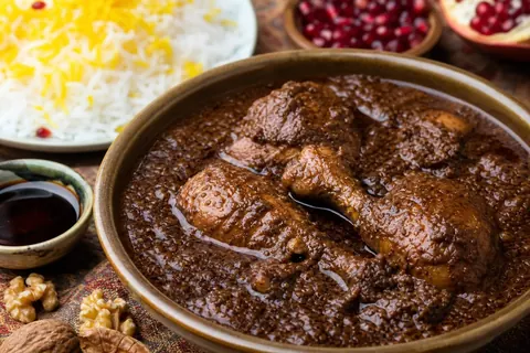 فسنجان مرغ با گردوی روغن‌افتاده در ظرف سرو ایرانی